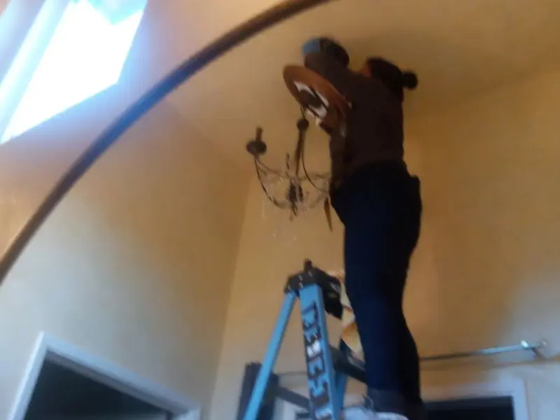 Electrician installing a chandelier in a Mountain Brook residence